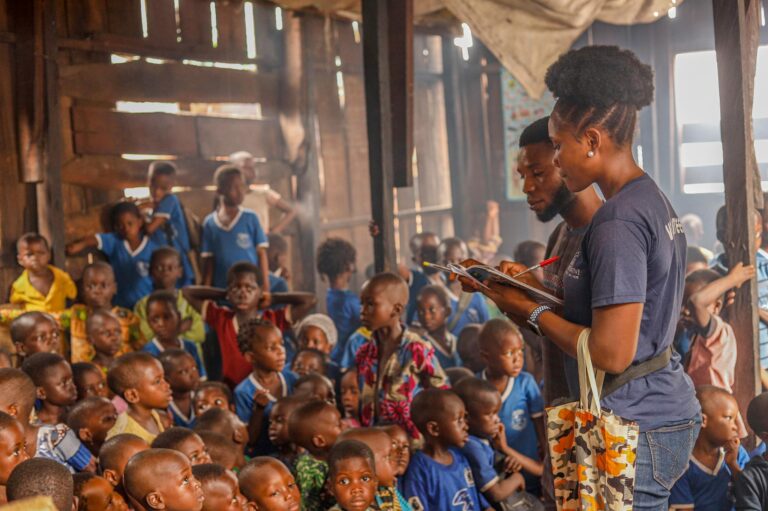 Volunteers conduct an educational session for children in an indoor community space.